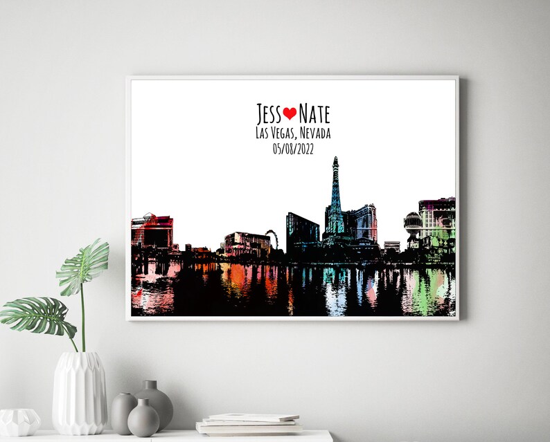 May include: A black and white silhouette of the Las Vegas skyline with a red heart and the text "Jess &hearts; Nate Las Vegas, Nevada 05/08/2022". The skyline is reflected in a body of water with colorful reflections.