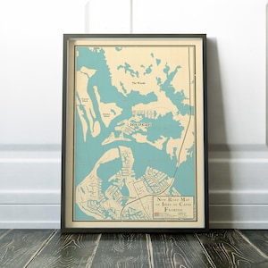 May include: A vintage style road map of Isles of Capri, Florida. The map is printed on cream colored paper with blue water features and green land features. The map shows the location of "The Woods", "Isles of Capri", and "Marco Island".