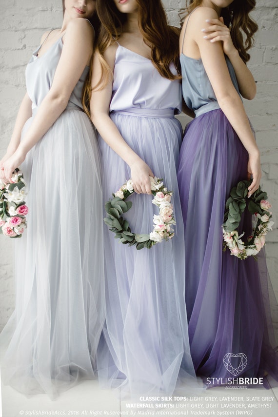 Two Beautiful Bridesmaids Girls Blonde And Brunette Ladies Wearing Elegant  Full Length Lavender Violet Tulle One Shoulder Bridesmaid Dress And Holding  Flower Bouquets European Old Town Location For Wedding Day Stock Photo -