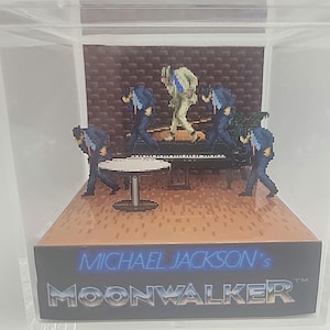 May include: A pixelated diorama featuring Michael Jackson's Moonwalker. The scene includes a piano, a small table, and several pixelated figures in suits. The diorama is encased in a clear box, with the title "MICHAEL JACKSON'S MOONWALKER" displayed on the base.