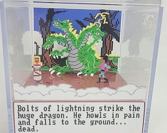 Puede incluir: Diorama de arte pixelado que muestra un dragón verde de tres cabezas alcanzado por un rayo. La escena incluye una figura, árboles y el texto: "Bolts of lightning strike the huge dragon. He howls in pain and falls to the ground... dead."