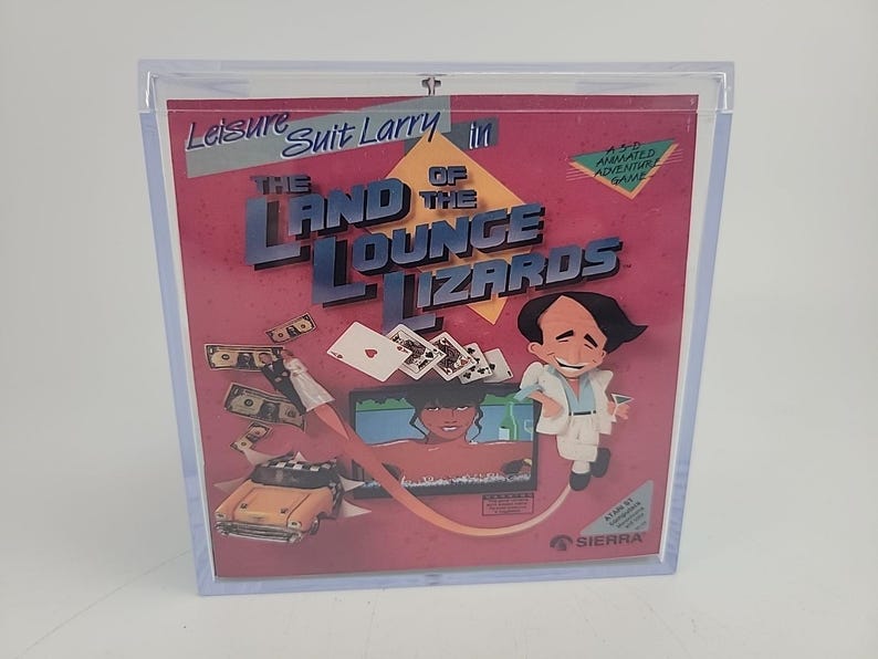 Puede incluir: Una caja de videojuego vintage de "Leisure Suit Larry in The Land of the Lounge Lizards". La ilustraci&oacute;n de la caja presenta un hombre de dibujos animados, un coche, dinero, naipes y una mujer en una pantalla. El juego es para Atari ST.