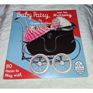 May include: A book cover titled Baby Patsy and her Nursery by Queen Holden featuring a black baby carriage with a pink blanket and a baby inside. The background is red and blue with the text 80 Pieces to Play with and a badge stating A New Queen Holden Book.