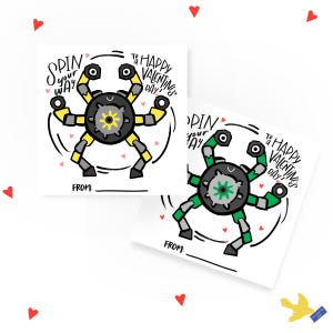以下が含まれることがあります： 回転する腕を持つロボットが描かれた、印刷可能なバレンタインデーカード2枚。左側のカードのロボットは黄色、右側のカードのロボットは緑色です。両方のカードには、「Spin your way to a Happy Valentine's Day!」と「From:」のテキストが書かれています。
