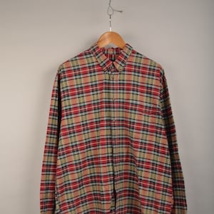 May include: A long-sleeved button-up shirt in a red, green and tan plaid pattern.