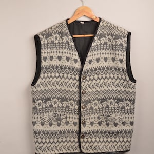 Op de afbeelding: Een wit en zwart gepatroneerd vest met een knoopsluiting. Het vest heeft een zwarte bies en een zwarte voering.