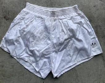 May include: White athletic shorts with a black Adidas logo on the right leg.