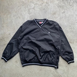 Puede incluir: Chaqueta cortavientos negra con ribetes blancos y un pequeño logotipo "W" blanco en el pecho.
