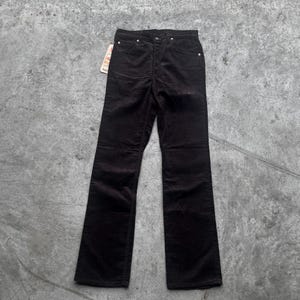 May include: Dark brown corduroy pants with a classic five-pocket design. The pants have a straight leg and a button and zipper closure. A price tag is attached to the pants.
