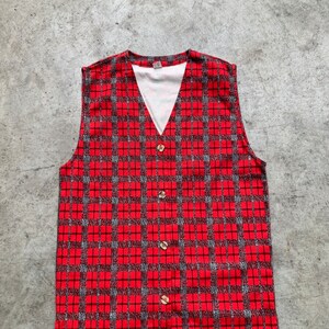 Op de afbeelding: Een rood en zwart geruit, mouwloos vest met een V-hals en knoopsluiting.