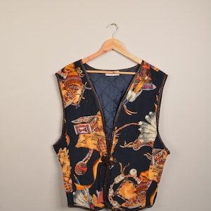 Può includere: Un gilet nero con bordino in pelle marrone e una stampa colorata di ispirazione nativa americana. Il gilet ha una chiusura a cravatta sul davanti.
