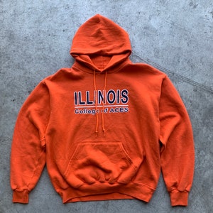 Op de afbeelding: Oranje hoodie met de tekst "ILLINOIS College of ACES" in witte en blauwe letters.