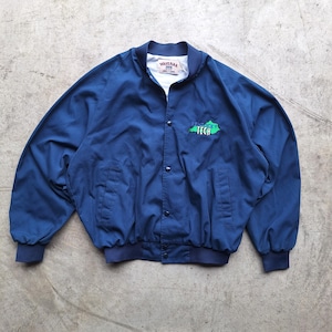 Op de afbeelding: Een marineblauwe bomberjack met een witte kraag en manchetten. De jas heeft een groen en wit geborduurd ontwerp met de tekst "Virginia Tech". De jas heeft een knoopsluiting en twee voorzakken.