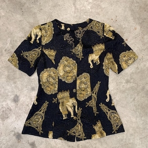 May include: A black short-sleeved button-up shirt with a gold and cream patterned design featuring elephants and ornate details.