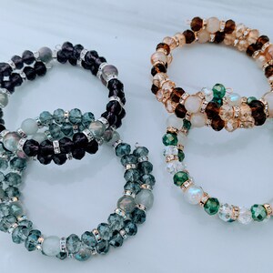 Peut inclure: Trois bracelets en perles avec différentes combinaisons de couleurs. Un bracelet est brun et beige, un autre est vert et blanc, et le dernier est noir et vert.