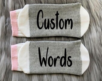 May include: A pair of gray and white socks with pink trim. The socks have the words "Custom Words" printed on them.