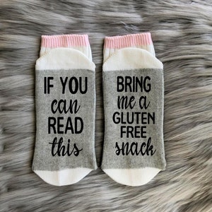 May include: A pair of grey and white socks with pink trim. One sock says "If you can read this" and the other sock says "Bring me a gluten free snack".