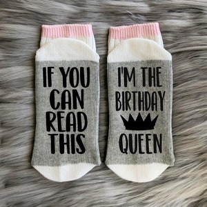 May include: A pair of gray and white socks with pink trim. One sock says "If you can read this" and the other sock says "I'm the birthday queen" with a crown graphic.