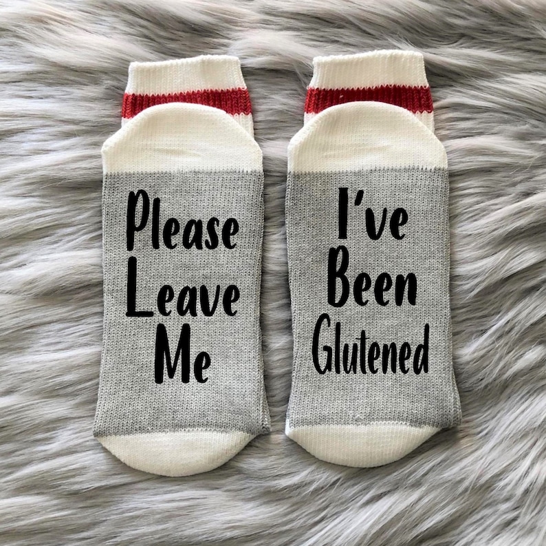K&ouml;nnte beinhalten: Ein Paar graue und wei&szlig;e Socken mit roten Streifen. Eine Socke sagt "Please Leave Me" und die andere sagt "I've Been Glutened".