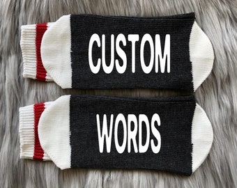 May include: A pair of black socks with white and red stripes. The socks have the words "CUSTOM" and "WORDS" printed on them.