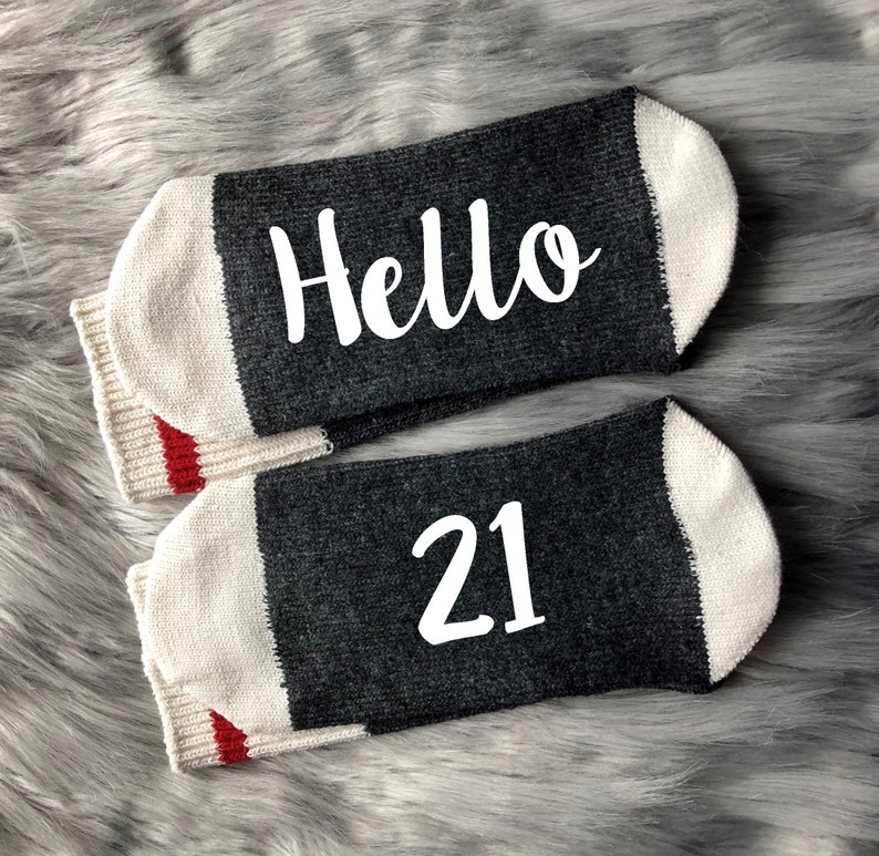 May include: A pair of gray and white socks with red trim. One sock says "Hello" and the other says "21".