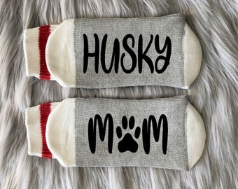 May include: A pair of grey and white socks with red stripes. One sock says "Husky" and the other says "Mom" with a paw print.