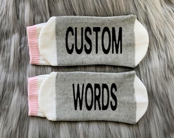 May include: A pair of gray and white socks with pink trim. The socks have the words "CUSTOM WORDS" printed on them.