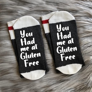 May include: A pair of black and white socks with red stripes. The socks have the text "You Had me at Gluten Free" on them.