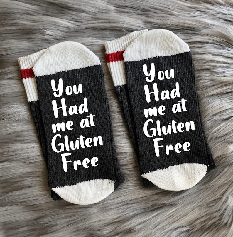 May include: A pair of black and white socks with red stripes. The socks have the text "You Had me at Gluten Free" on them.