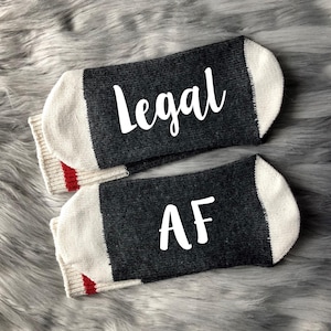 May include: A pair of gray and white socks with red trim. One sock says "Legal" and the other says "AF".