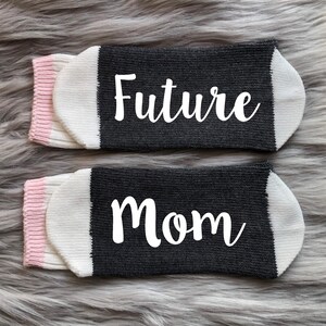 May include: A pair of black and white socks with pink trim. One sock says "Future" and the other says "Mom".