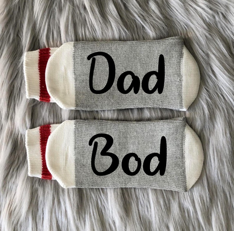 May include: A pair of gray socks with red and white stripes at the top. One sock says "Dad" and the other says "Bod".