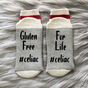May include: A pair of gray and white socks with red stripes. One sock says "Gluten Free #celiac" and the other says "For Life #celiac".