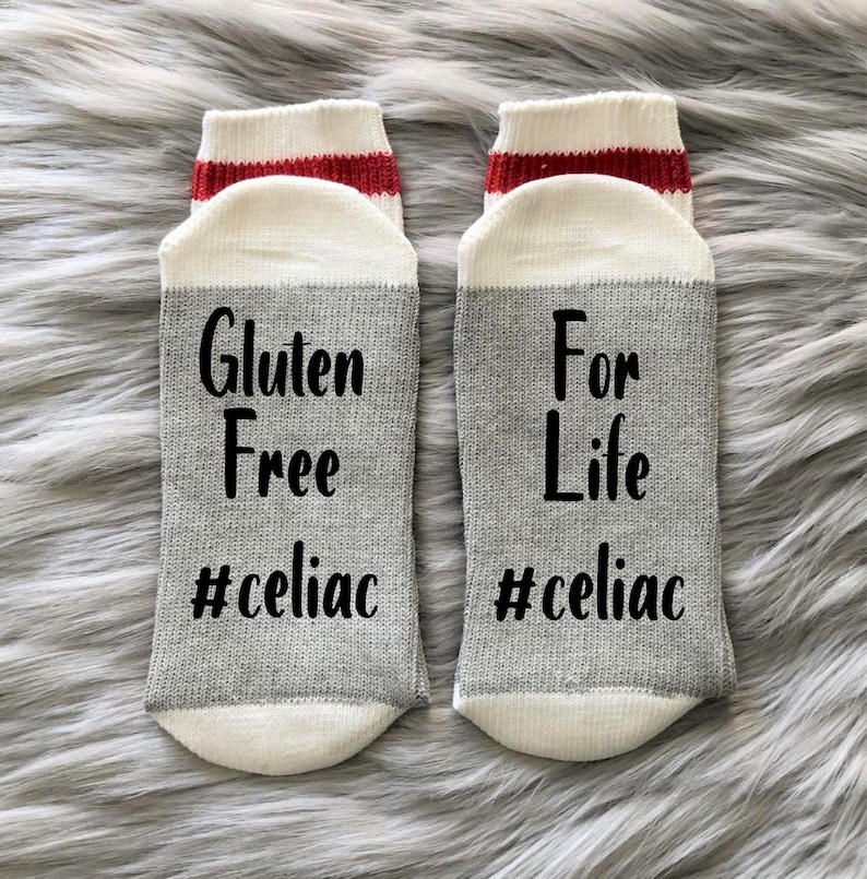 May include: A pair of gray and white socks with red stripes. One sock says "Gluten Free #celiac" and the other says "For Life #celiac".