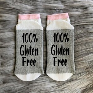 May include: A pair of gray and white socks with pink trim. The socks have the text "100% Gluten Free" printed on them.