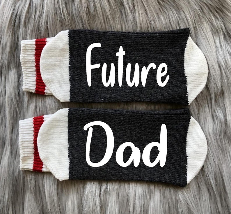 May include: A pair of black socks with white trim and red stripes. One sock says "Future" and the other says "Dad".