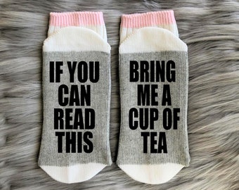 May include: A pair of gray and white socks with pink trim. One sock reads "If you can read this" and the other sock reads "Bring me a cup of tea".