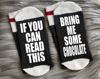 May include: A pair of black and white socks with red stripes. One sock says "If you can read this" and the other sock says "Bring me some chocolate".