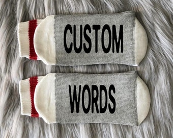 May include: A pair of gray and white socks with red stripes. The socks have the words "CUSTOM" and "WORDS" printed on them.