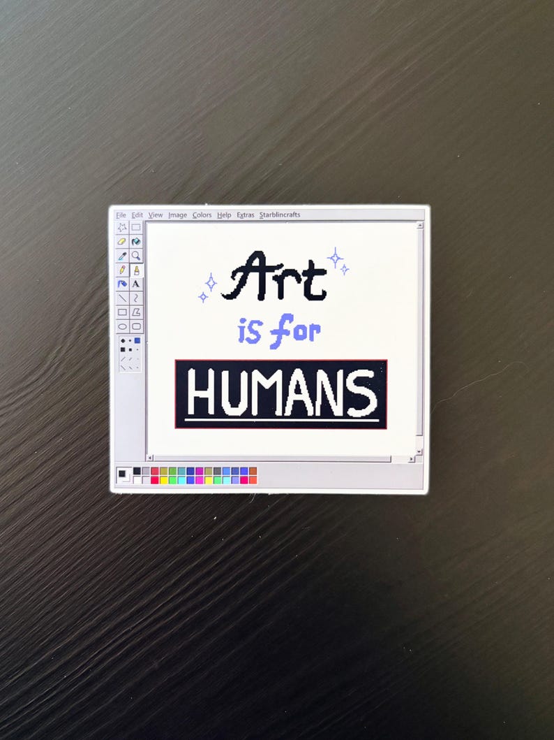 May include: A white sticker with a computer-generated art program interface. The text "Art is for HUMANS" is displayed in black and blue. The sticker has a black background.