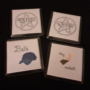 Könnte beinhalten: Vier quadratische Untersetzer mit Kreuzstichmustern. Jeder Untersetzer zeigt ein Wort: "Bitch" mit einem Pentagramm, "Jerk" mit einem Pentagramm, "Balls" mit einer blauen Form und "Hey assbutt" mit einer Grafik.