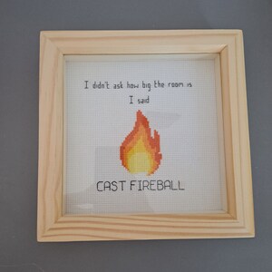 May include: A framed cross-stitch with the text "I didn't ask how big the room is. I said cast fireball." and a pixelated image of a flame.
