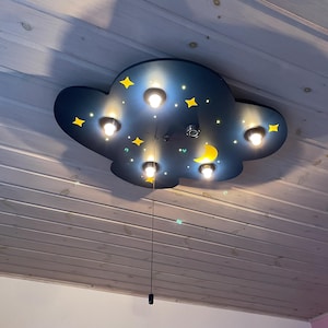 May include: A blue and yellow cloud-shaped ceiling light fixture with a pull chain. The light fixture has five light bulbs and a crescent moon and stars design.