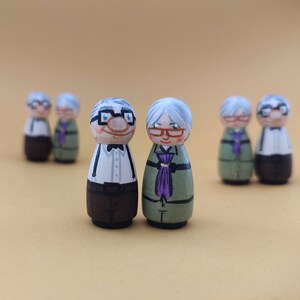 May include: Set of ten hand-painted wooden figurines depicting older adults with grey hair and glasses. The figurines are wearing various clothing, including a white shirt with a bow tie, a green shirt with a purple scarf, and a brown shirt with a white collar.