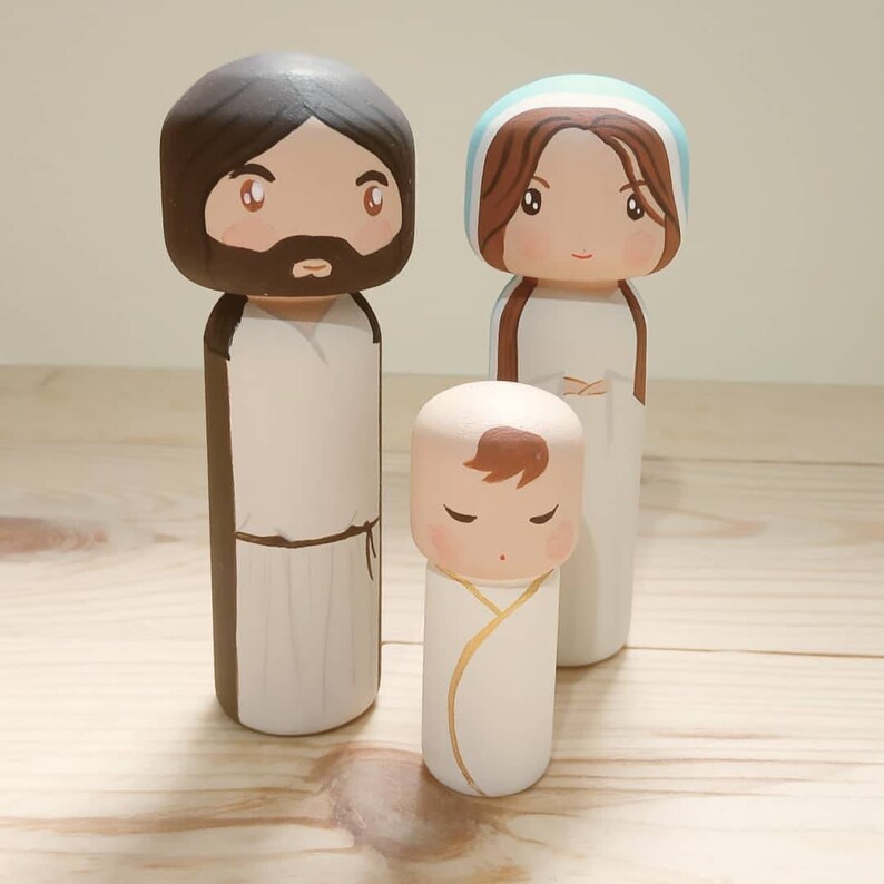 Puede incluir: Un conjunto de tres mu&ntilde;ecos de madera que representan a la Sagrada Familia. El mu&ntilde;eco del padre lleva una t&uacute;nica marr&oacute;n, el mu&ntilde;eco de la madre lleva una t&uacute;nica azul y blanca, y el mu&ntilde;eco del beb&eacute; lleva un pa&ntilde;al blanco.