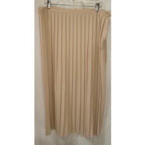 May include: A beige pleated skirt hanging on a hanger. The skirt is made of a lightweight fabric and features vertical pleats that run the length of the garment. The skirt appears to be knee-length or slightly longer.