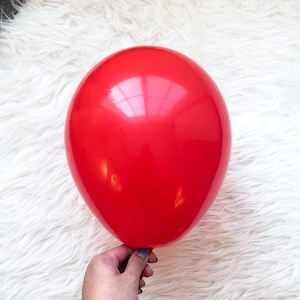 May include: A bright red balloon against a white fluffy background.