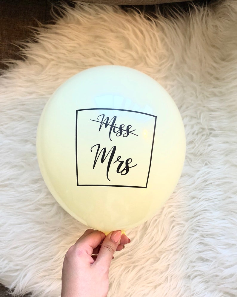 May include: A pale yellow balloon with a black square and the text "Miss Mrs" printed on it.
