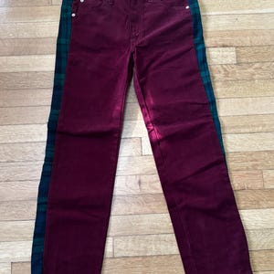 May include: A pair of maroon jeans with green and black plaid fabric panels down the sides.