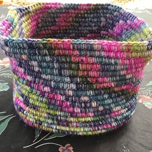 May include: A crocheted basket with a colorful, multi-colored yarn in shades of pink, green, blue, and white.